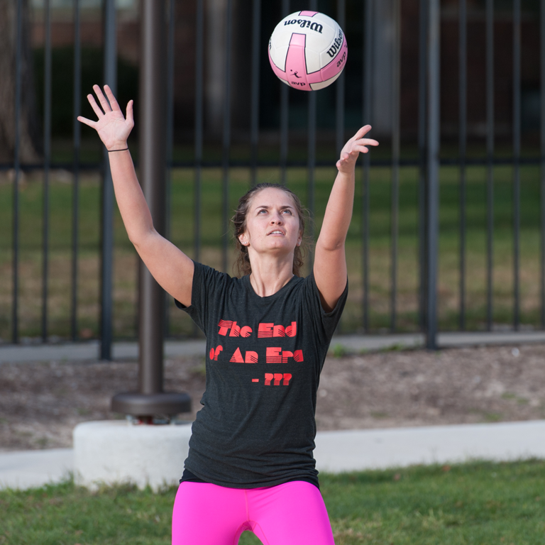 A woman serving a volleyball.