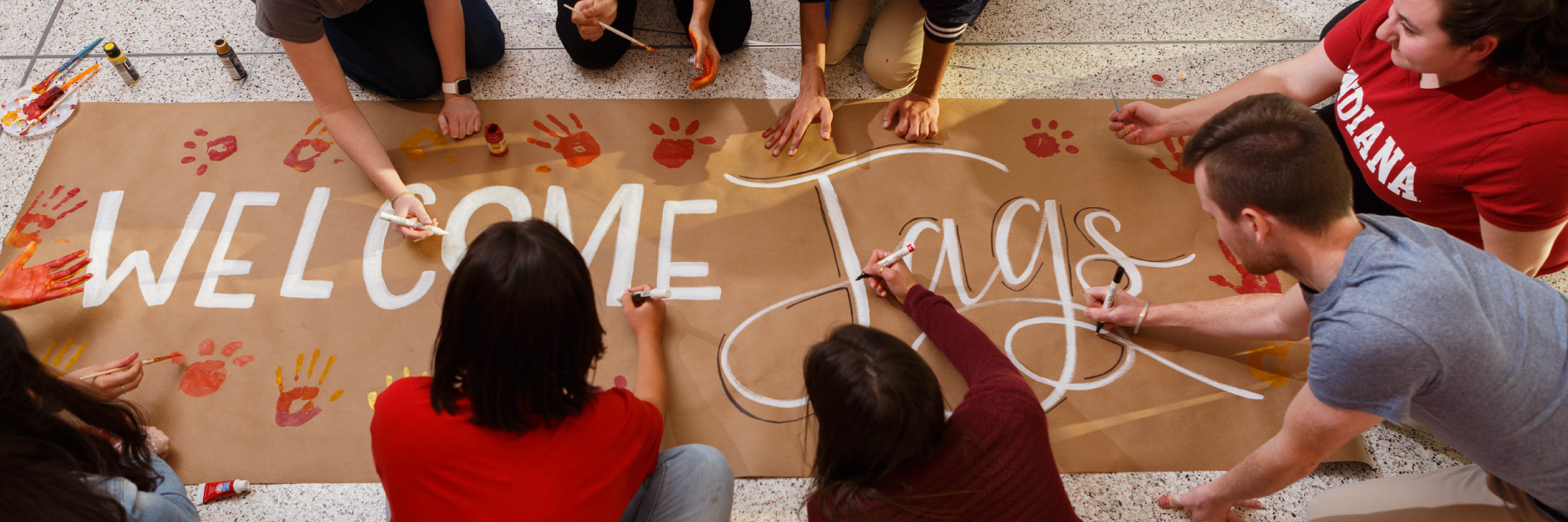 Student painting a sign that says Welcome Jags.