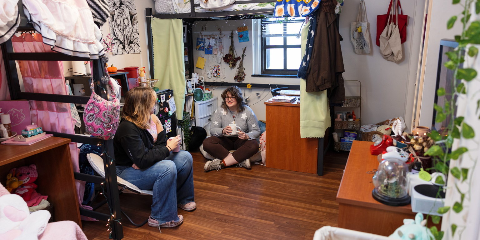 Two students talking in a dorm room.