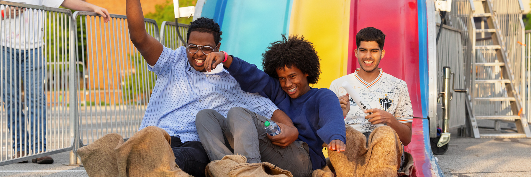Three men smiling as they go down a slide at Jagapalooza.